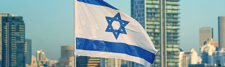 Flag of Israel on the background of modern city. Israeli flag against the background of skyscrapers in Tel Aviv in front of blue sky.